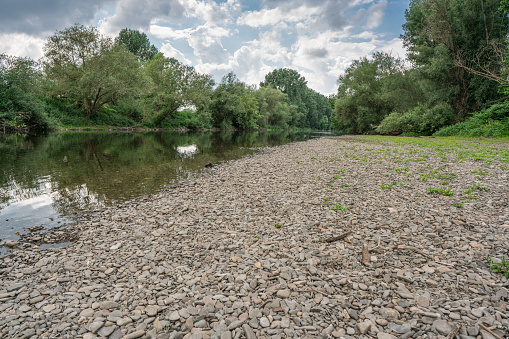 Flat gravel bank on a small river on a cloudy spring day. Downstream