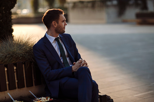 Young businessman in a suit sitting on a bench