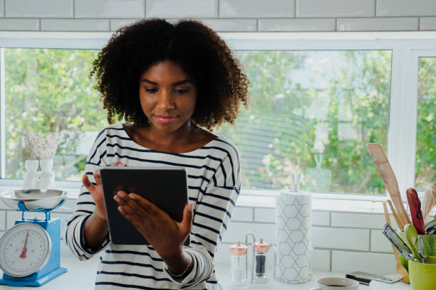 istock Young female in the kitchen browsing tablet for recipe, copy space 1248699317