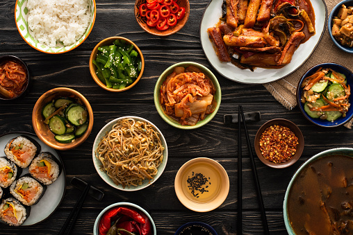 top view of korean traditional dishes near chopsticks and cotton napkin on wooden surface