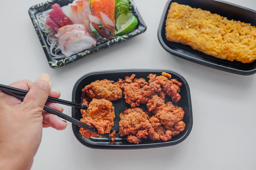 Close up shot of Asian woman eating chicken karage and some other variant of Japanese food for dinner, during Coronavirus lockdown