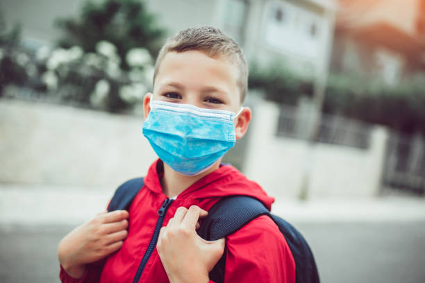 l’enfant porte le masque facial pendant le coronavirus et l’éclosion de grippe - little boys only outdoors little boys elementary age photos et images de collection