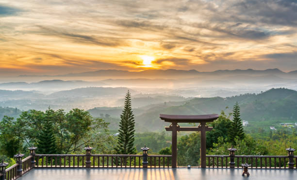 istock Dawn in front of temple gate with impressive colorful clouds in sky shines under mist valley 1248705514
