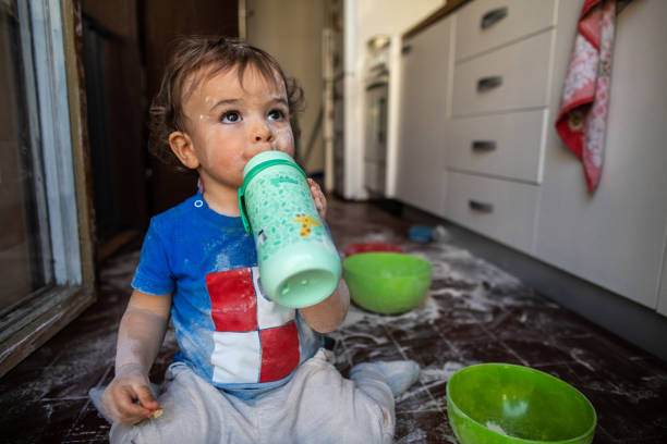 istock Messy little boy drinking water from baby bottle at kitchen 1248706939