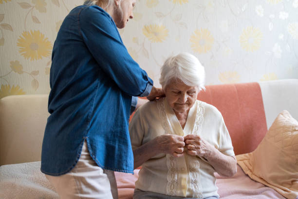 Woman helping senior woman dress in her bedroom Woman helping senior woman dress in her bedroom getting dressed stock pictures, royalty-free photos & images