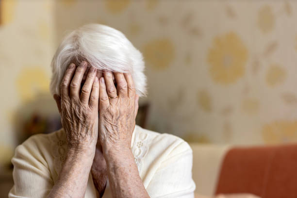 istock Senior woman holding head in hands in despair 1248708306