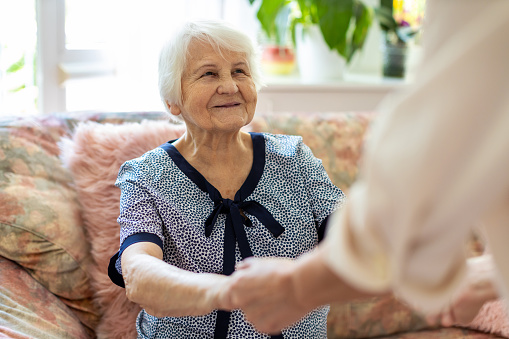 Mujer cuidadora en casa apoyando a la anciana para levantarse del sofá en el hogar de cuidado photo