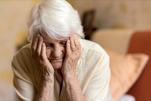 Senior woman holding head in hands in despair