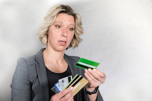 Business woman posing in studio in a bad mood with a credit card in her hands.