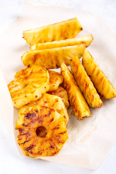 istock Heap of grilled pineapple slices on white background. 1248710074