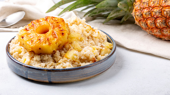 Sweet rice with grilled pineapples and raisins on gray plate on concrete background. Vegetarian food concept .