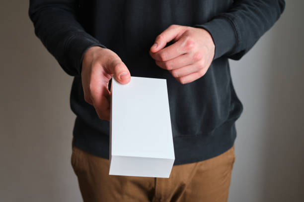 istock Man holding in hand small paper box. Blank packing, empty space. Male with a new package. Postal service, delivery. White paper. Gift box, present. Box close up. People communication. Carton case 1248713274