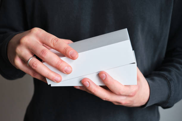 Man holding in hand small paper box. Blank packing, empty space. Male with a new package. Postal service, delivery. White paper. Gift box, present. Box close up. People communication. Carton case