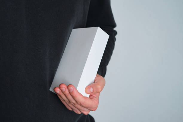 istock Man holding in hand small paper box. Blank packing, empty space. Male with a new package. Postal service, delivery. White paper. Gift box, present. Box close up. People communication. Carton case 1248713308