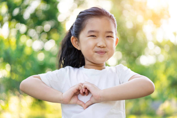 menina fazendo gesto em forma de coração - heart shape child human hand childhood - fotografias e filmes do acervo