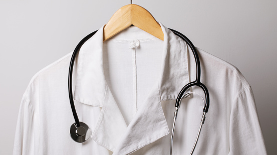 Old medical gown and a stethoscope on a hanger, close-up