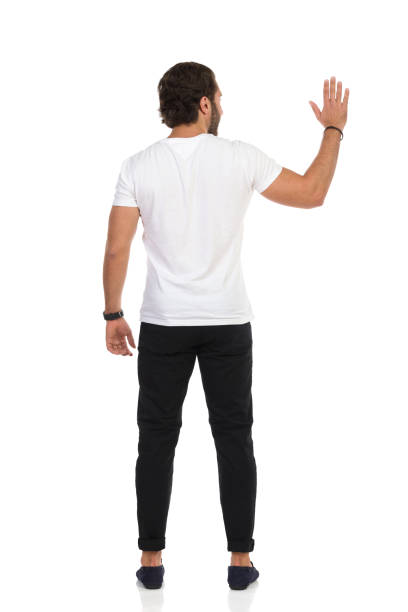 side view of relaxed casual man looking up at something while standing  on white background, full length picture