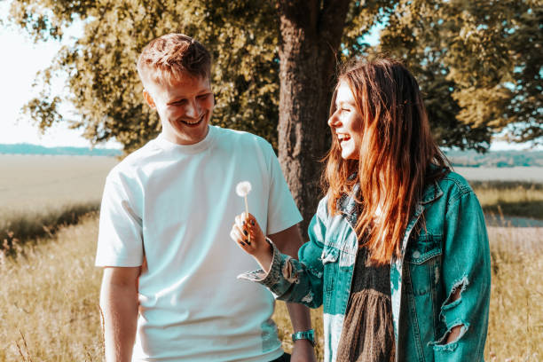 istock Young Couple Together Outdoors Blowing Dandelion 1248718300