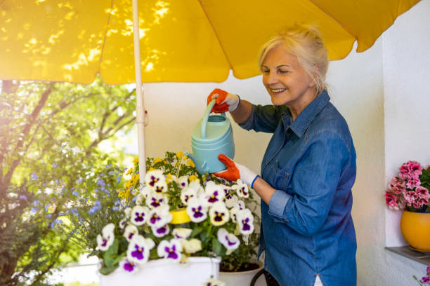 mujer mayor cuidando sus plantas en el balcón - florida house patio real estate fotografías e imágenes de stock