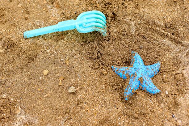 jouets en plastique oubliés pour enfants sur le sable sur la plage. concept de vacances, voyage, été, vacances, crise des affaires touristiques, verrouillage, annulation due au coronavirus, covide-19. - beach cancelled close up color image photos et images de collection