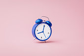 Blue alarm clock ringing on pink background with rush hour concept. Notification to wake up time or work. 3D rendering.