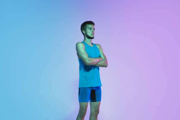 istock Full length portrait of active young caucasian running, jogging man on gradient studio background in neon light 1248721202