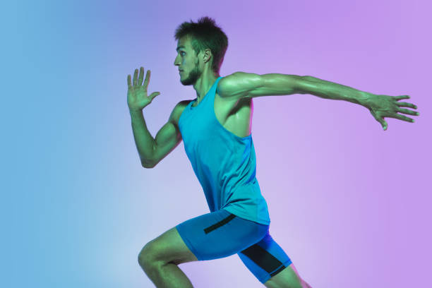 istock Full length portrait of active young caucasian running, jogging man on gradient studio background in neon light 1248721212