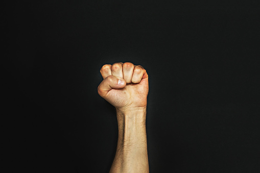 Male fist on a black background. Aggressiveness, masculinity, the concept of challenge.