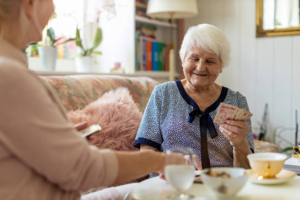 Senior woman and her adult daughter playing cards at home Senior woman and her adult daughter playing cards at home family playing card game stock pictures, royalty-free photos & images