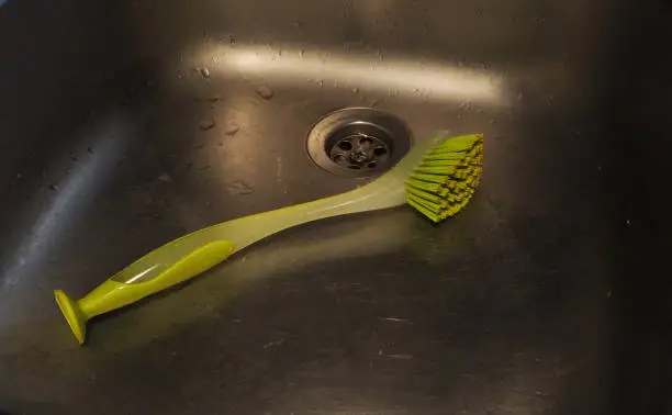 Green dishwashing brush in kitchen sink