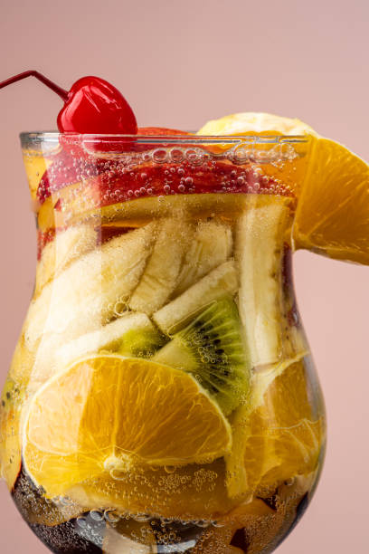 fruit salad of fresh fruits and berries in a transparent glass on a gradient background