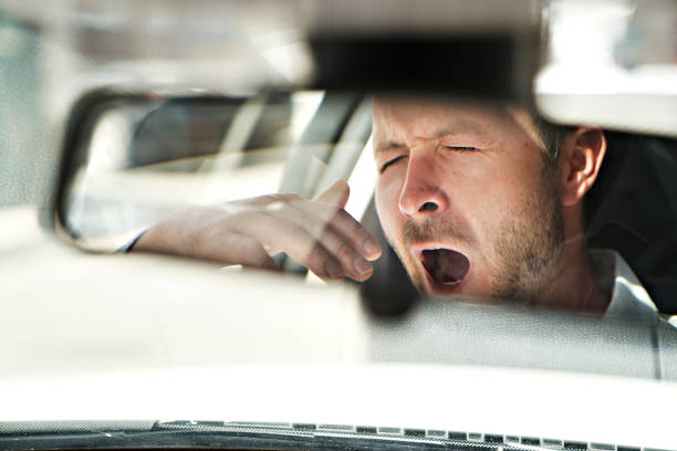 hombre bostezar en su coche porque está tan cansado - cansado fotografías e imágenes de stock