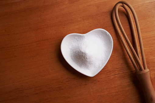 directly above heart shape bowl of baking soda on the wooden background