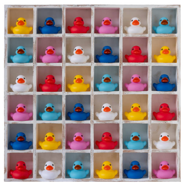 istock Many different vibrant colored rubber ducks in white wood pigeon hole compartments, isolated on white, clipping path included. 1248730200