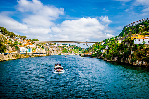 A boat full of tourists on the Douro river in Porto during a sunny day of summer.