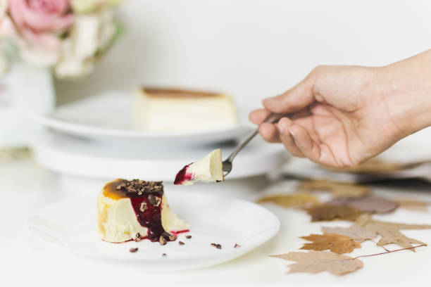 istock Hand with fork eating basque burnt cheesecake with mixed berry sauce topped with cacao nibs. 1248734046