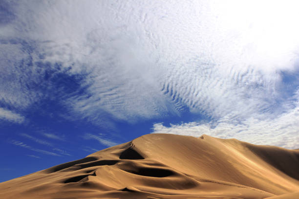 Golden sand dune 7 and white clouds on a sunny day in the Namib desert. Fantastic place for travelers and photographers.