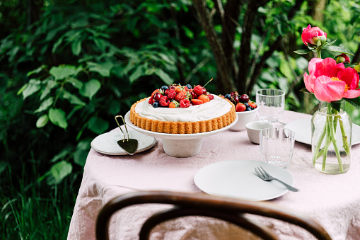 Homemade cheese cake served on table in garden outdoors. Breakfast table ready in garden.