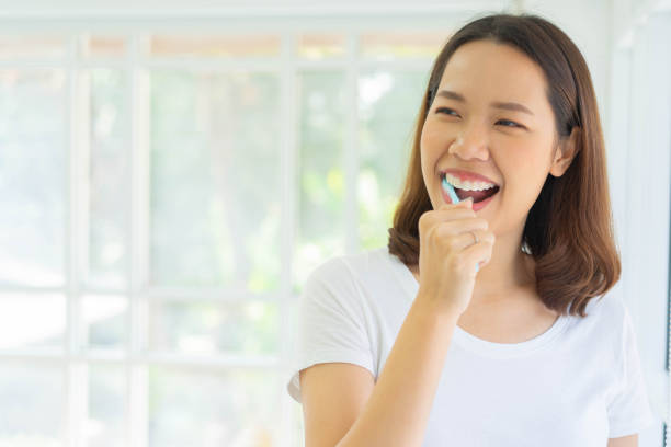 primo piano giovane donna asiatica che usa lo spazzolino da denti per lavarsi i denti in bagno al mattino con un concetto di vita sana e di routine - healthy lifestyle human teeth adult brushing foto e immagini stock