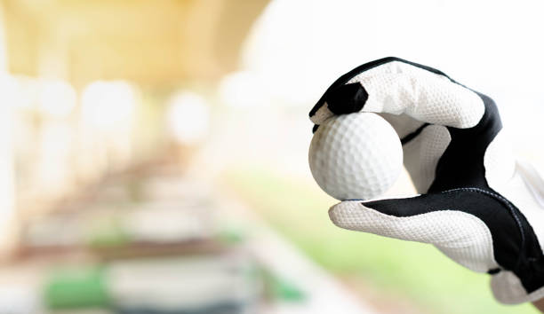 weibliche hand trägt weiße profihandschuhe mit der linken hand halten golfball vorbereitung, um den golfball zu treffen - golf power golf course challenge stock-fotos und bilder