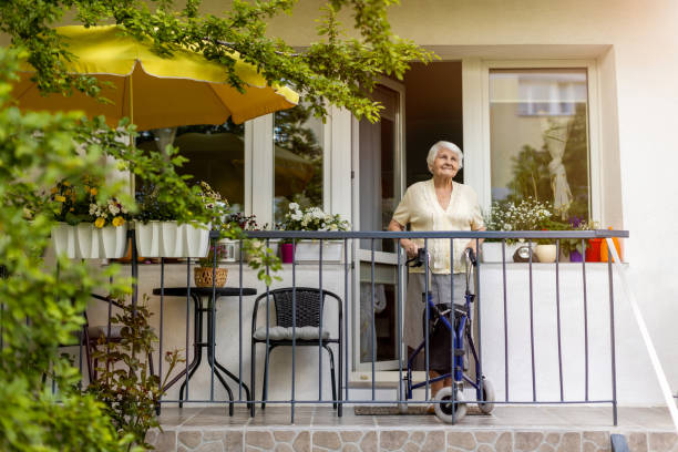 Senior woman with mobility walker standing on her balcony