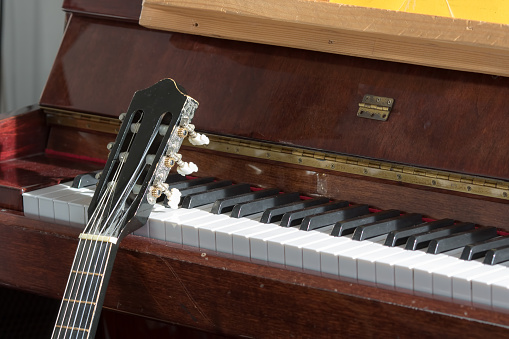 Classical music. Acoustic guitar resting on an old piano. Music teachers  teaching music,practice room close-up.