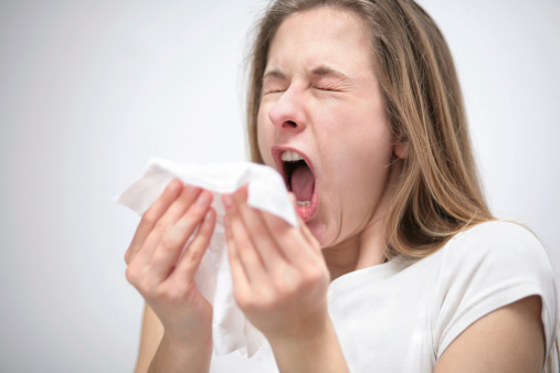 portrait of a young woman with tissue sneezing 