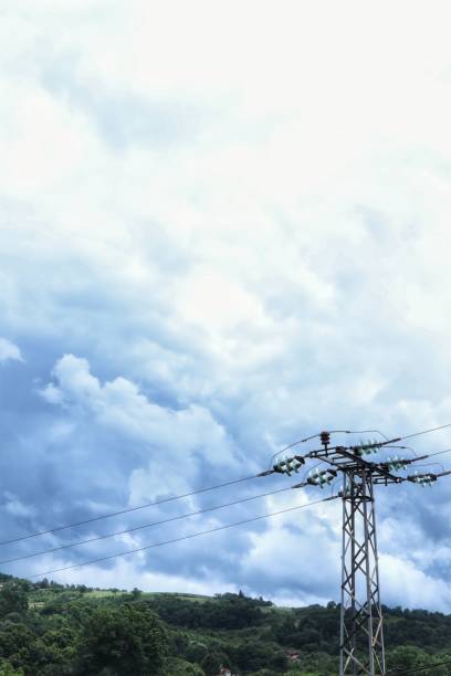 Cloudy sky, green hills, electricity cables.