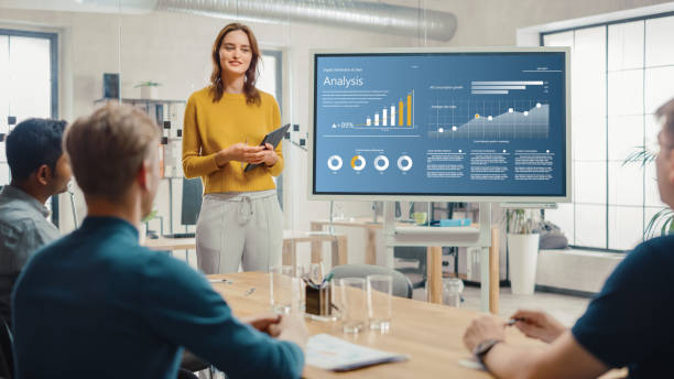 female chief analyst hält meeting-präsentation für ein team von ökonomen. sie zeigt digital interactive whiteboard mit wachstumsanalyse, diagrammen, statistiken und daten. menschen arbeiten im creative office. - entspannung grafiken stock-fotos und bilder