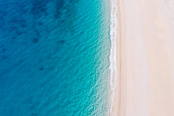 von oben nach unten luftansicht eines weißen sandstrandes am ufer eines wunderschönen türkisfarbenen meeres. - aerial stock-fotos und bilder