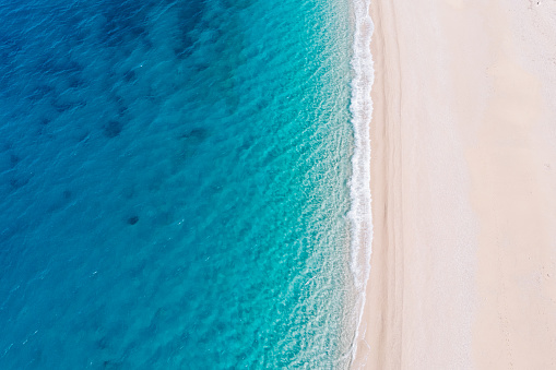 Top-down aerial view of a clean white sandy beach on the shores of a beautiful turquoise sea. Greece.