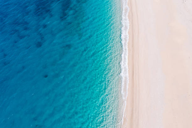 z lotu ptaka roztacza się widok na białą piaszczystą plażę nad brzegiem pięknego turkusowego morza. - summer beach multi colored vacations zdjęcia i obrazy z banku zdjęć