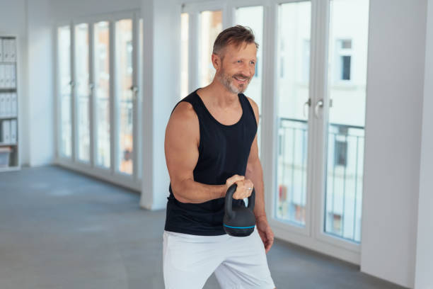 istock Happy motivated man lifting a kettlebell weight 1248748500