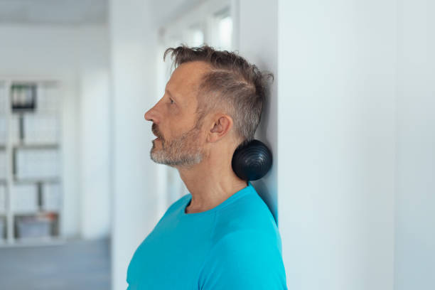 homme d’âge moyen utilisant un rouleau de massage sur un mur - massage ball photos et images de collection